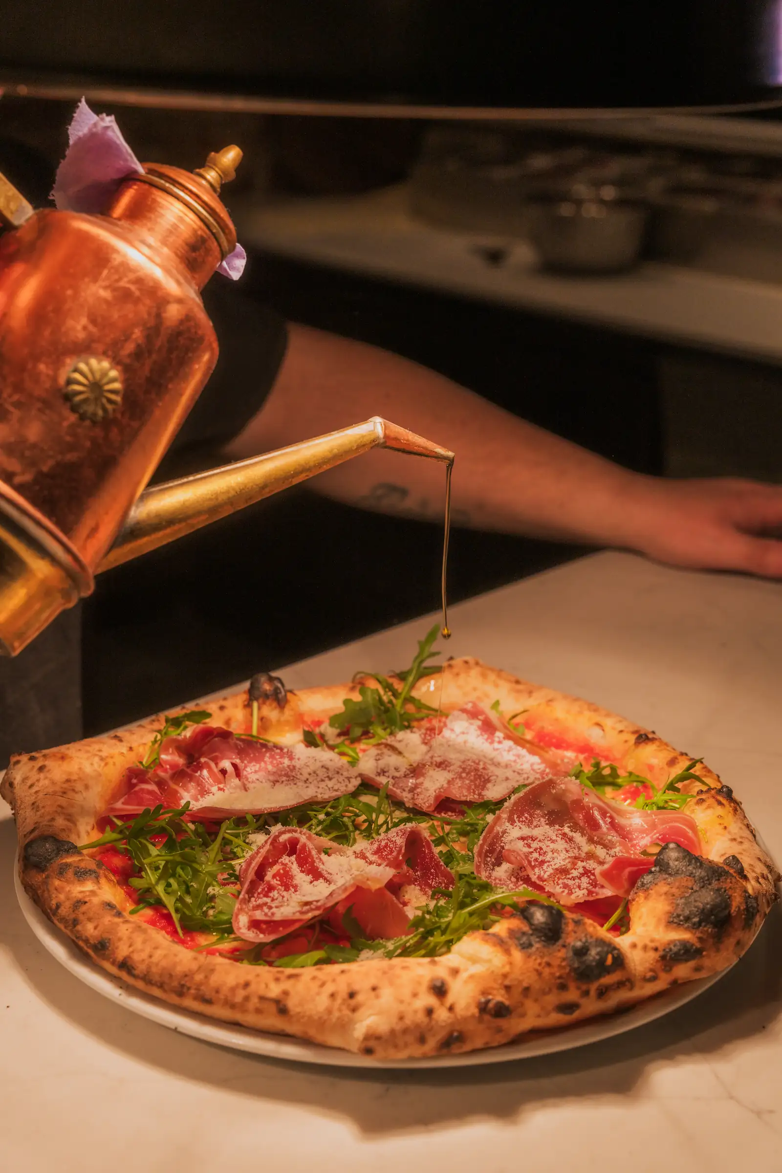 A chef is drizzling chilli oil onto a pizza