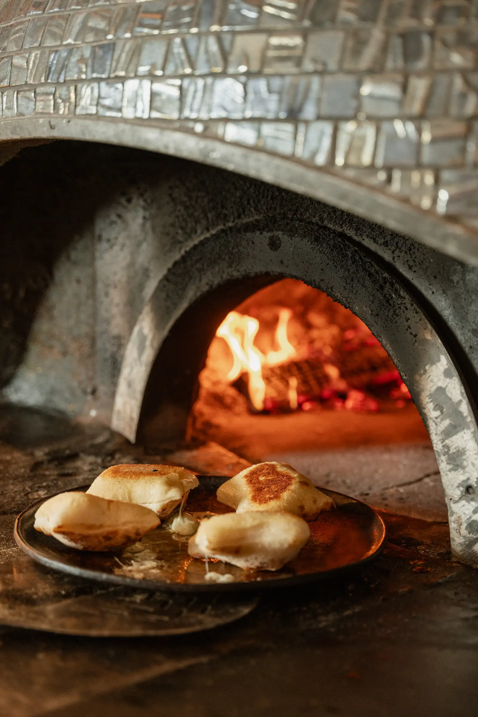 Some cooked food is sat in front of a wood fired pizza oven.