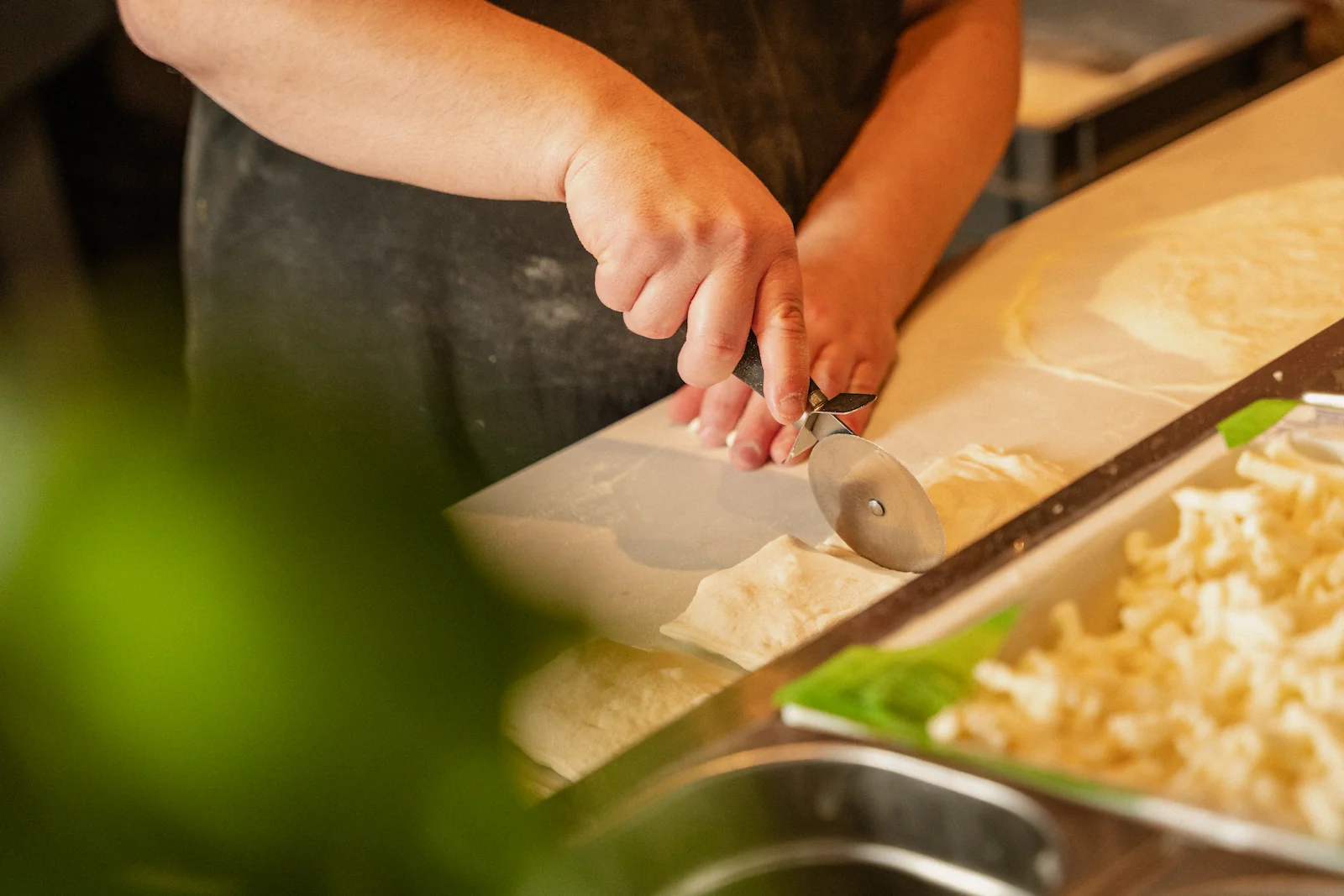 A chef is cutting dough with a circular cutter.