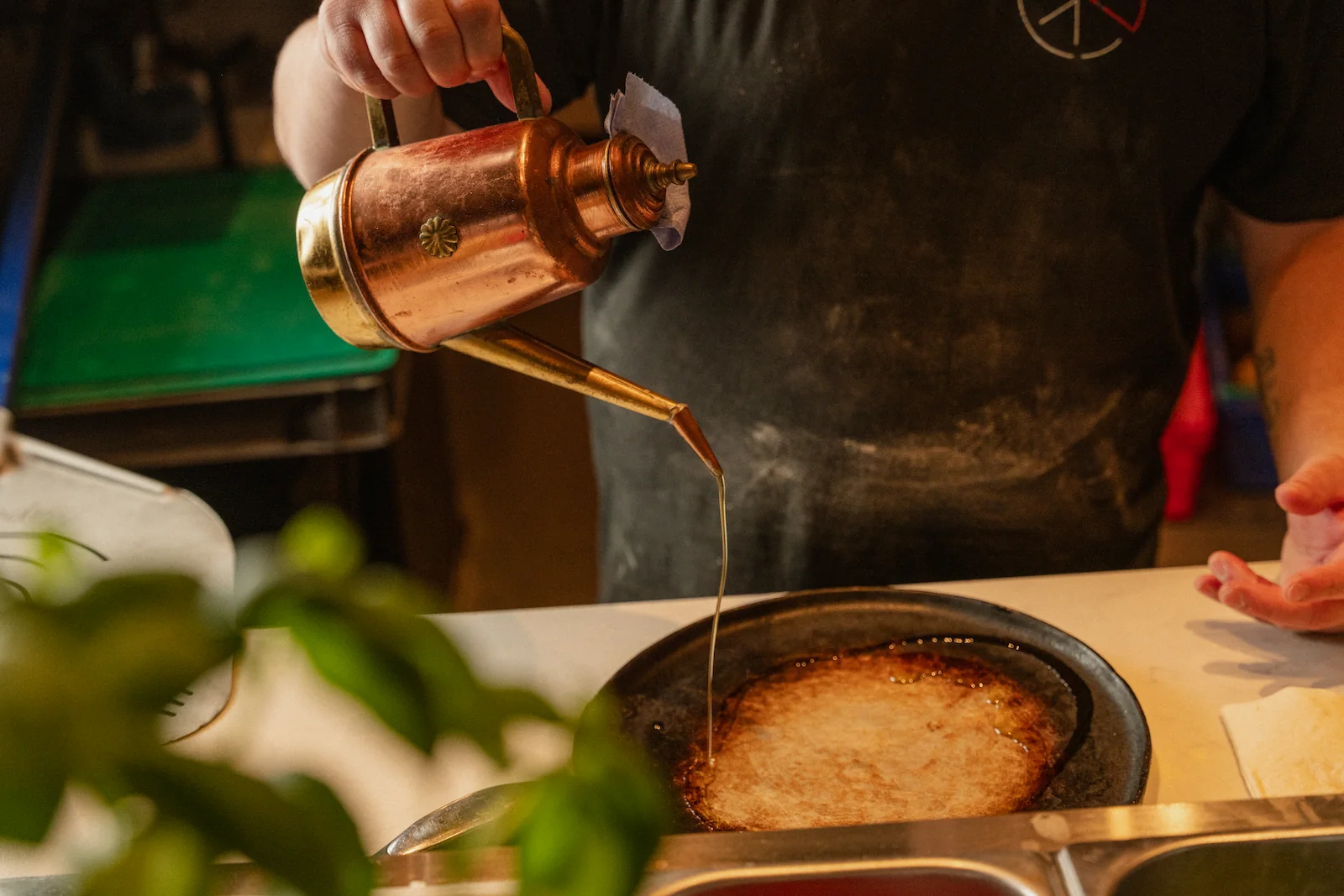 A chef is drizzling chilli oil onto a plate