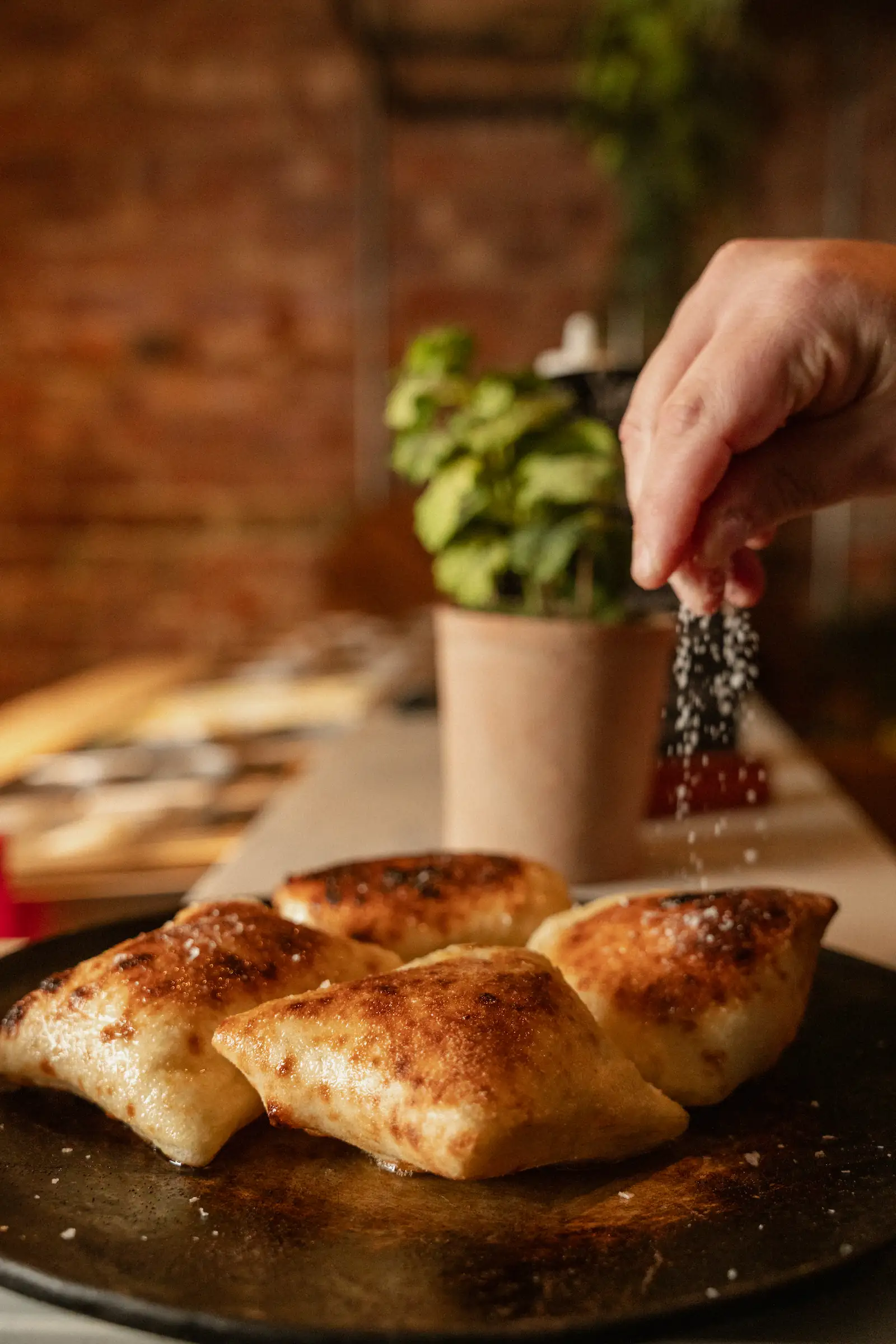 A chef is sprinking parmesan cheese onto a dish.