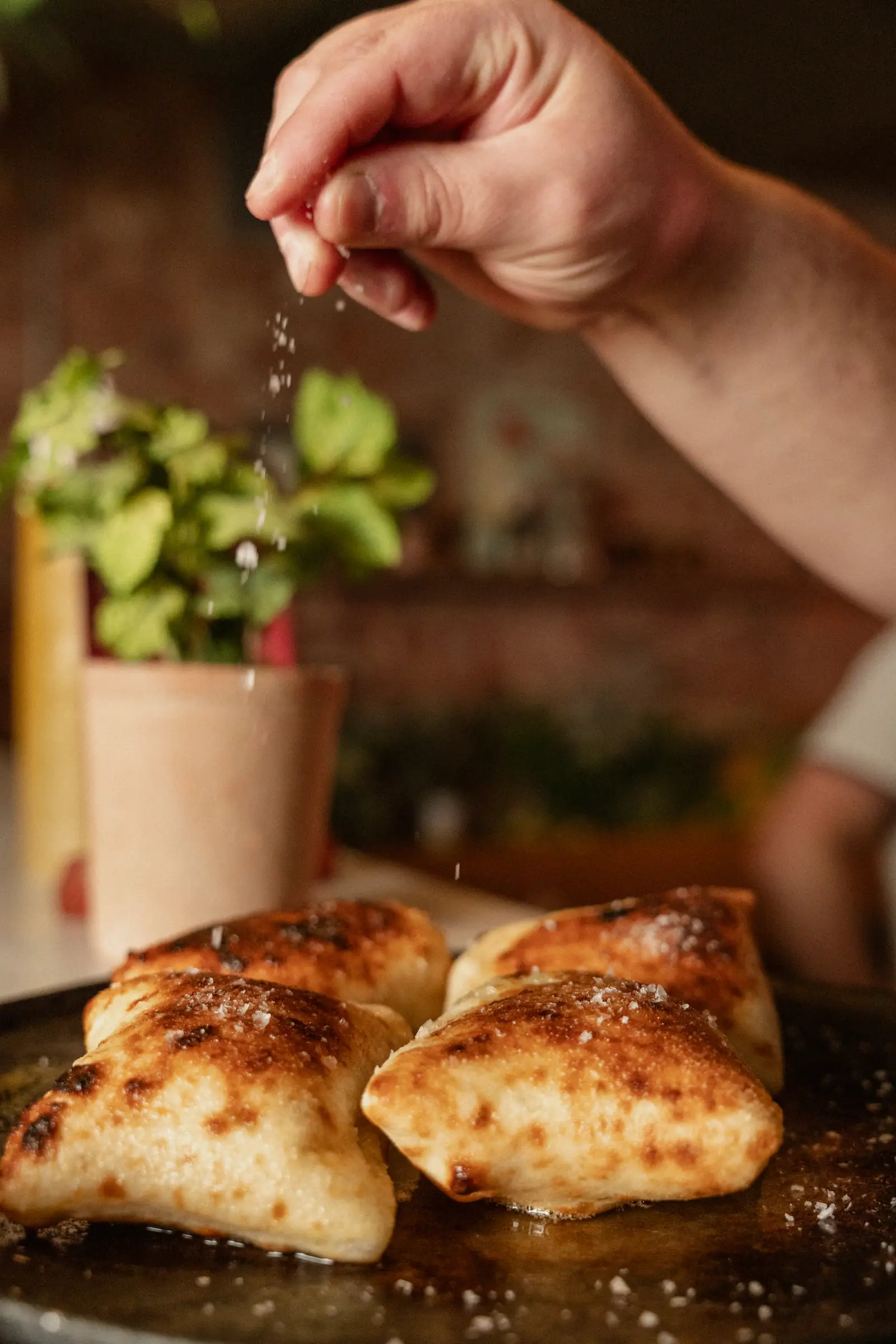 A chef is sprinking parmesan cheese onto a dish.