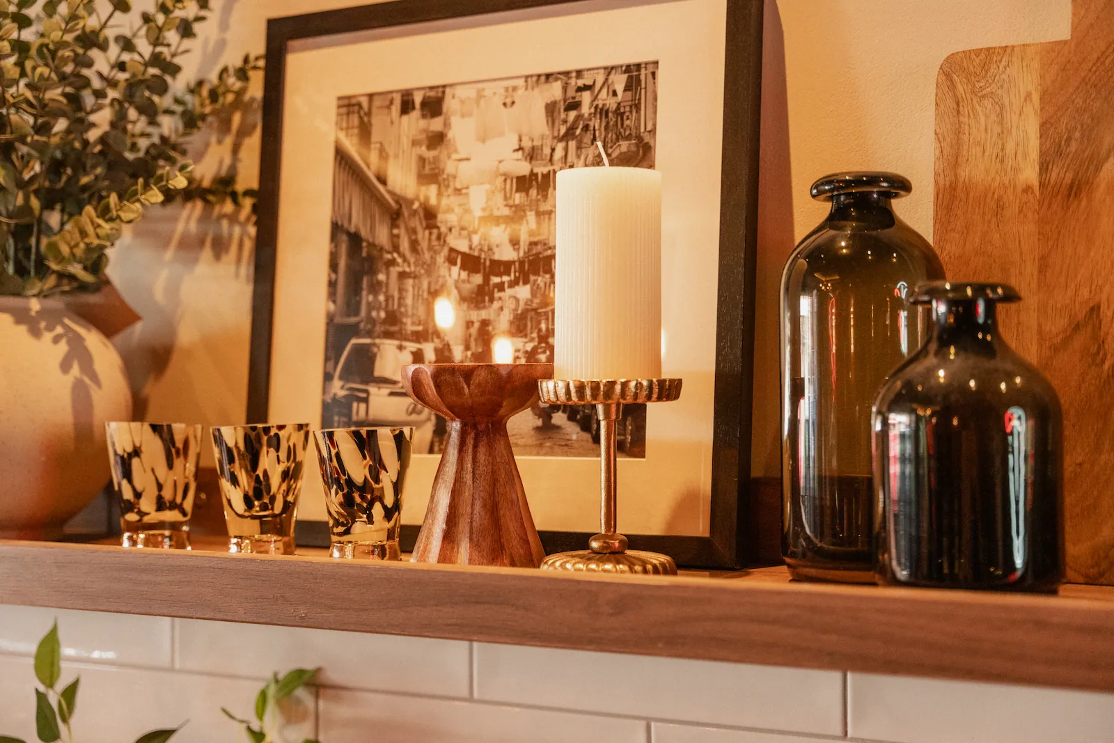 A photo of a shelf containing bottles, candles and a framed photo.