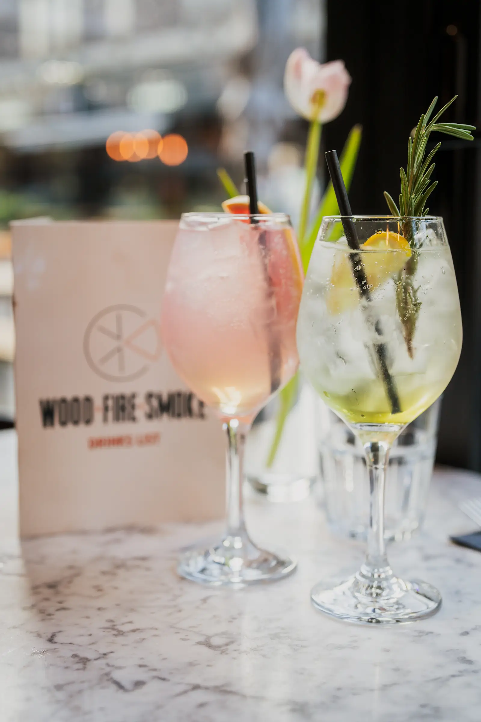 Photo of two fresh cocktails in front of a drinks menu.
