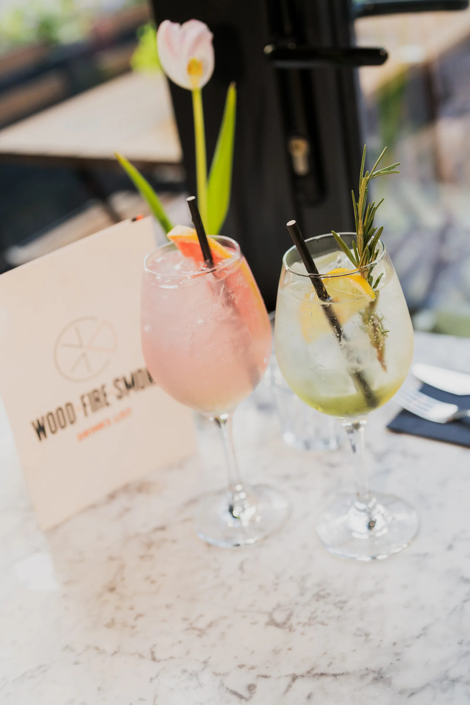 Photo of two fresh cocktails in front of a drinks menu.