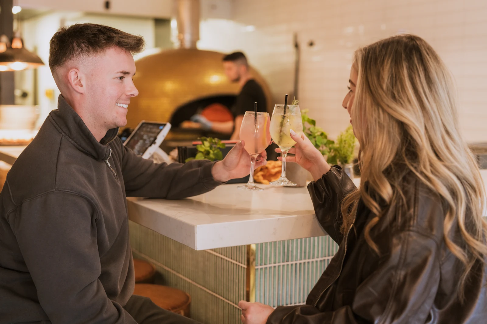 A man and woman are smiling and drinking cocktails.