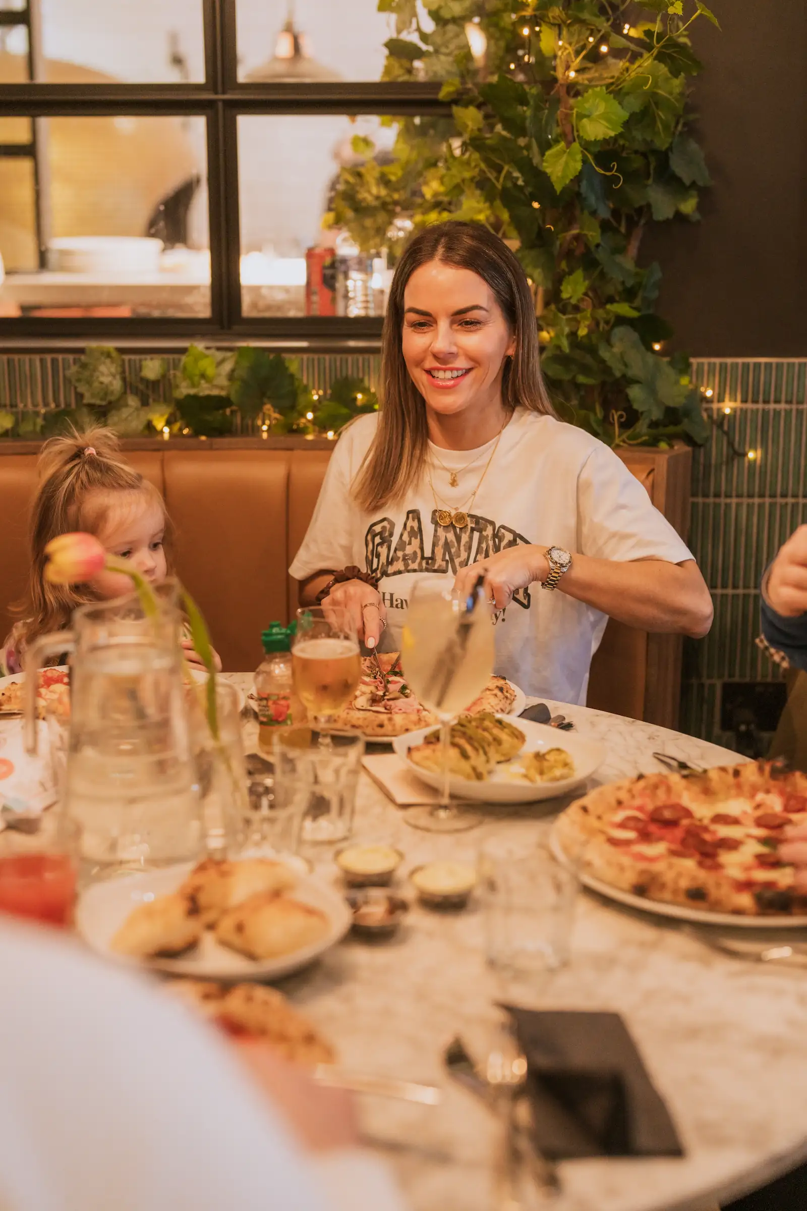 Photo of a woman smiling while eating pizza with her family.